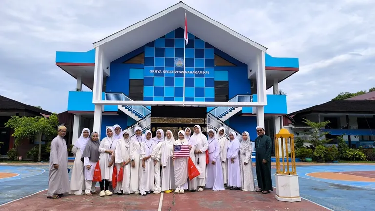 Siswa berbusana putih berfoto di depan bangunan bercorak biru