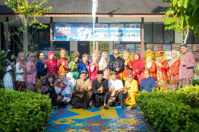 Warga sekolah berpakaian batik dan kebaya berfoto bersama di halaman sekolah